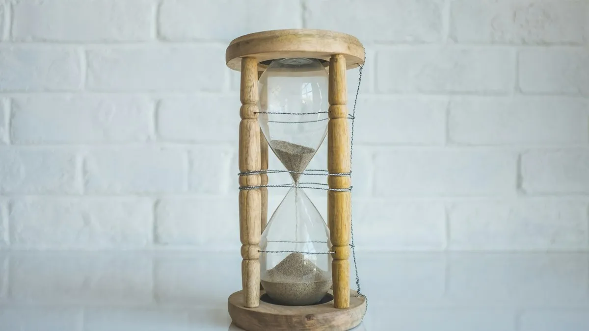 A wooden-framed hourglass in front of a white brick wall